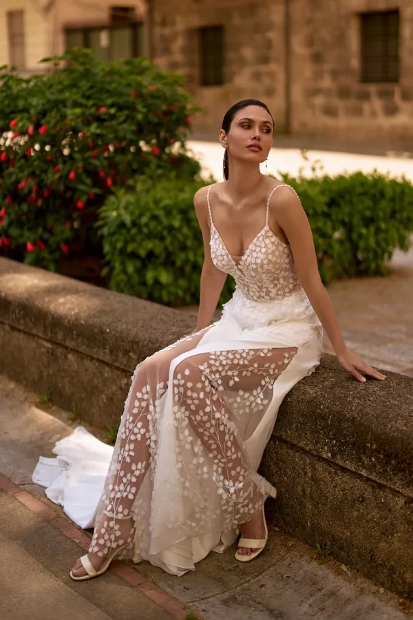 Mariée assise dévoilant la fente transparente à pétales d'une robe de mariée droite