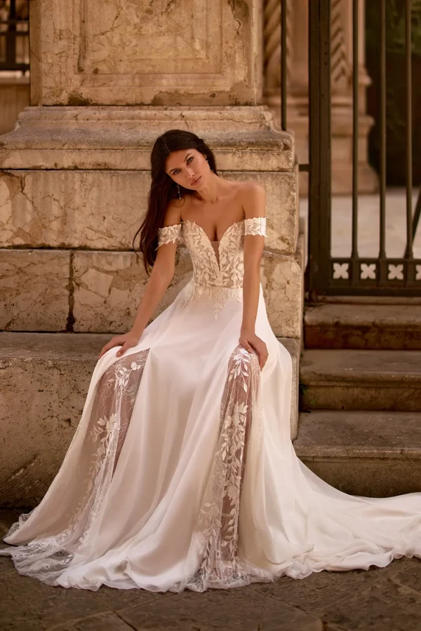 Mariée assise en robe droite en mousseline à épaules dénudées et fente en dentelle