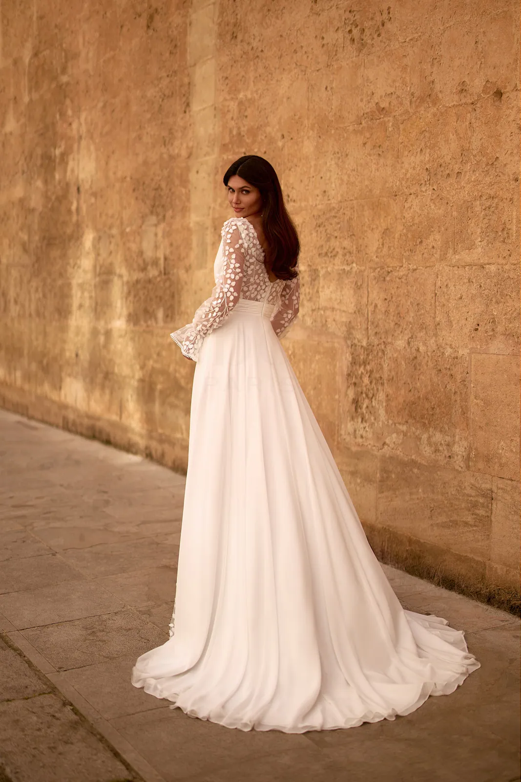 Dos et traîne d'une robe de mariée droite en mousseline à manches longues à pétales