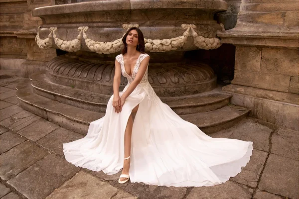 Mariée assise en robe droite fendue en mousseline, traîne étalée au sol