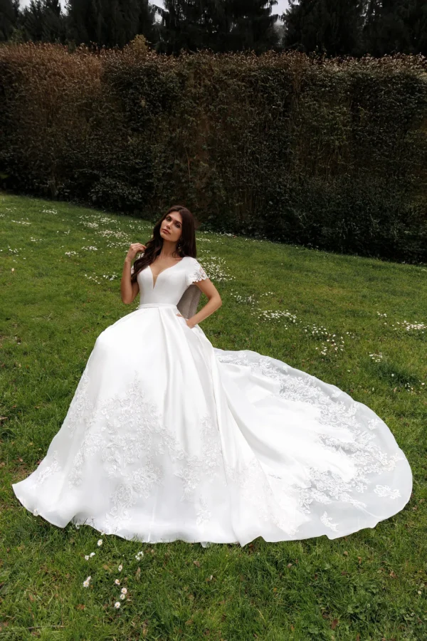 Mariée assise en robe princesse en mikado, traîne en dentelle étalée
