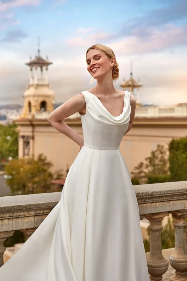 Col bénitier drapé et larges bretelles d'une robe de mariée princesse en satin