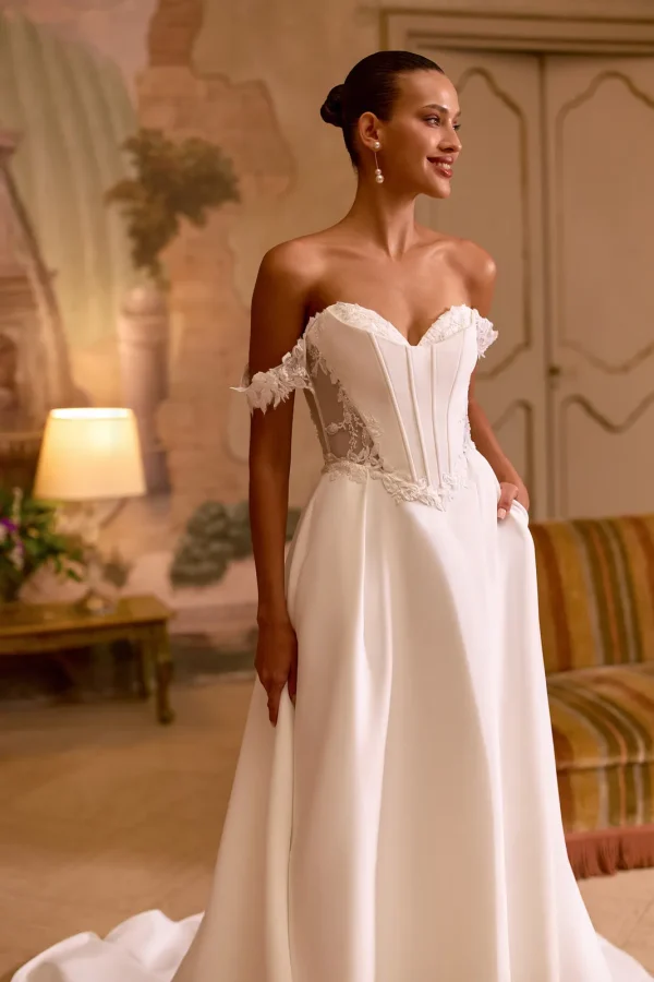 Bustier cœur corseté et bretelles tombantes en dentelle d'une robe de mariée princesse en satin