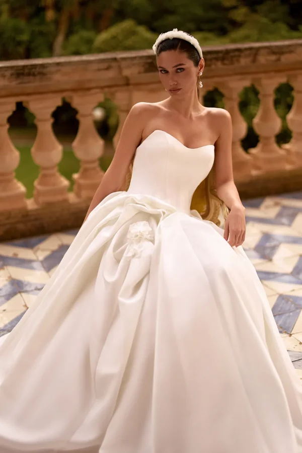 Mariée assise en robe princesse en satin à bustier cœur et jupe drapée