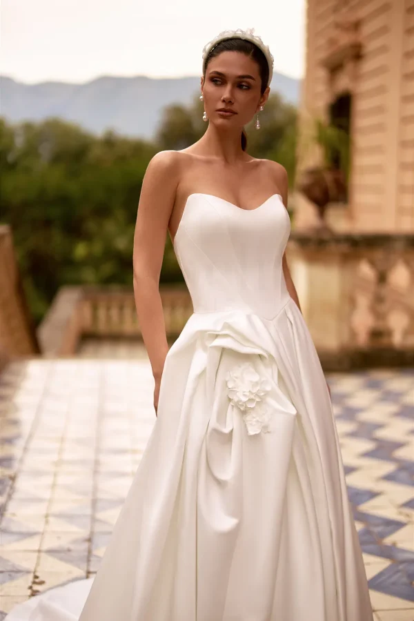 Fleur en satin drapée sur la jupe d'une robe de mariée princesse bustier