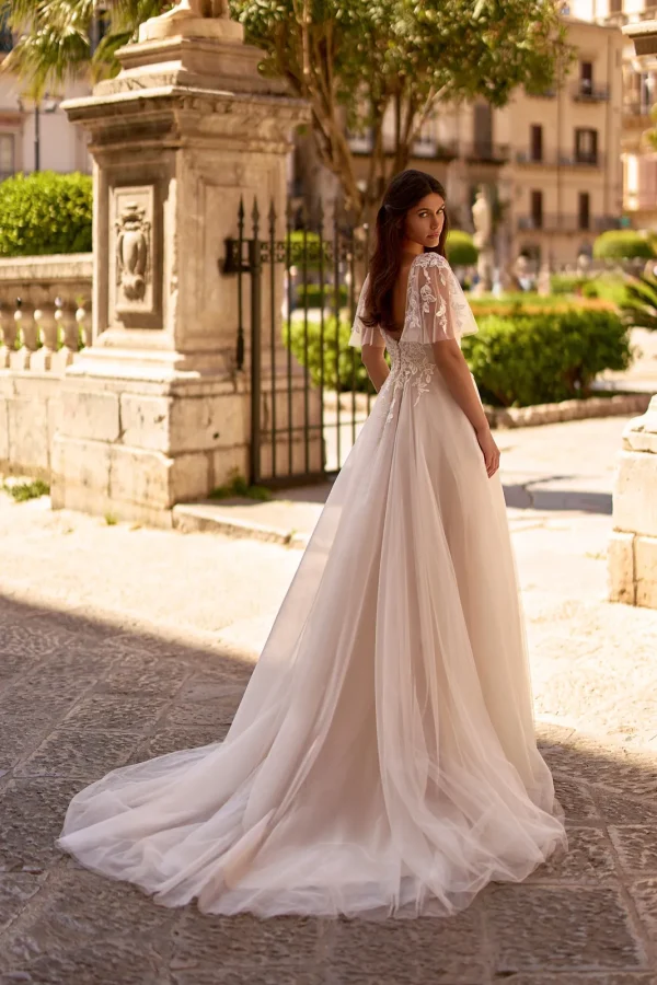 Dos et traîne en tulle d'une robe de mariée princesse nude à manches papillon