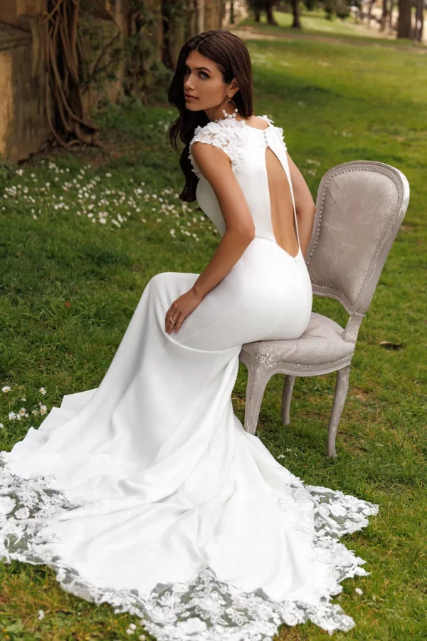 Mariée assise de dos en robe sirène en crêpe à dos ouvert et traîne en dentelle