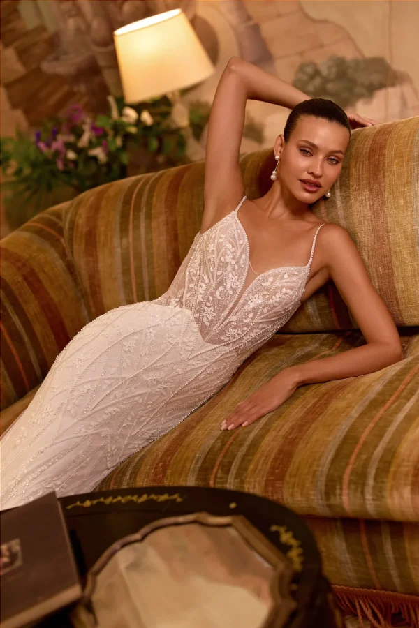 Mariée allongée sur un canapé en robe de mariée sirène brodée à fines bretelles