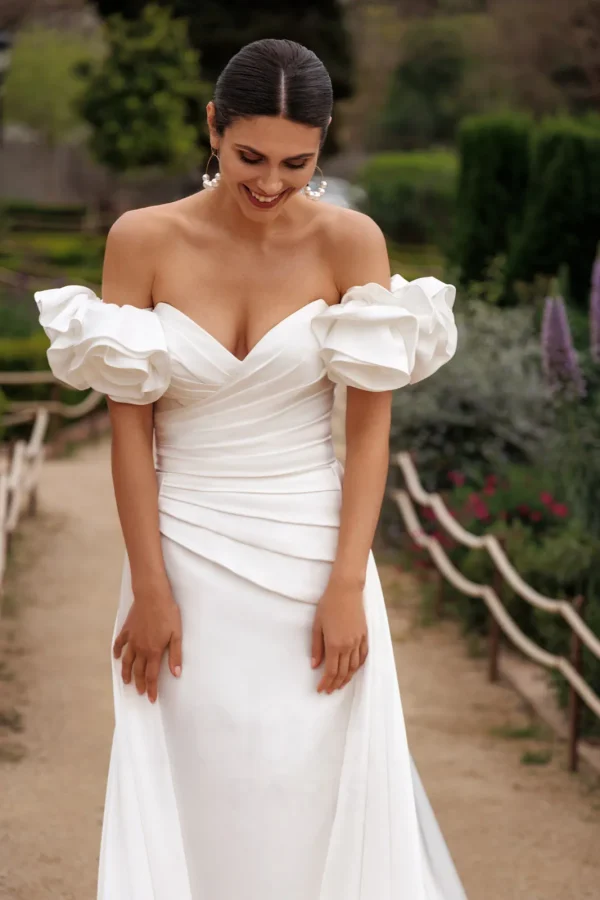 Épaules dénudées ornées de rosaces en satin d'une robe de mariée sirène drapée
