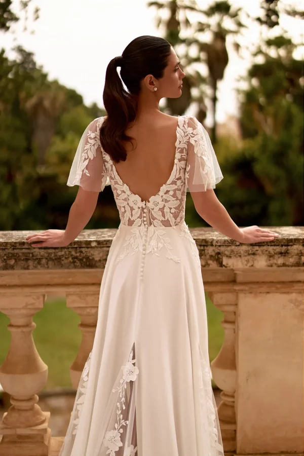 Dos nu en V boutonné et manches papillon d'une robe de mariée trapèze