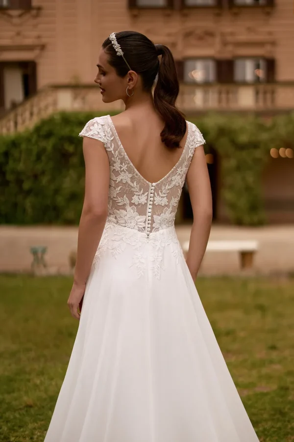 Dos en V en dentelle boutonné d'une robe de mariée trapèze à mancherons