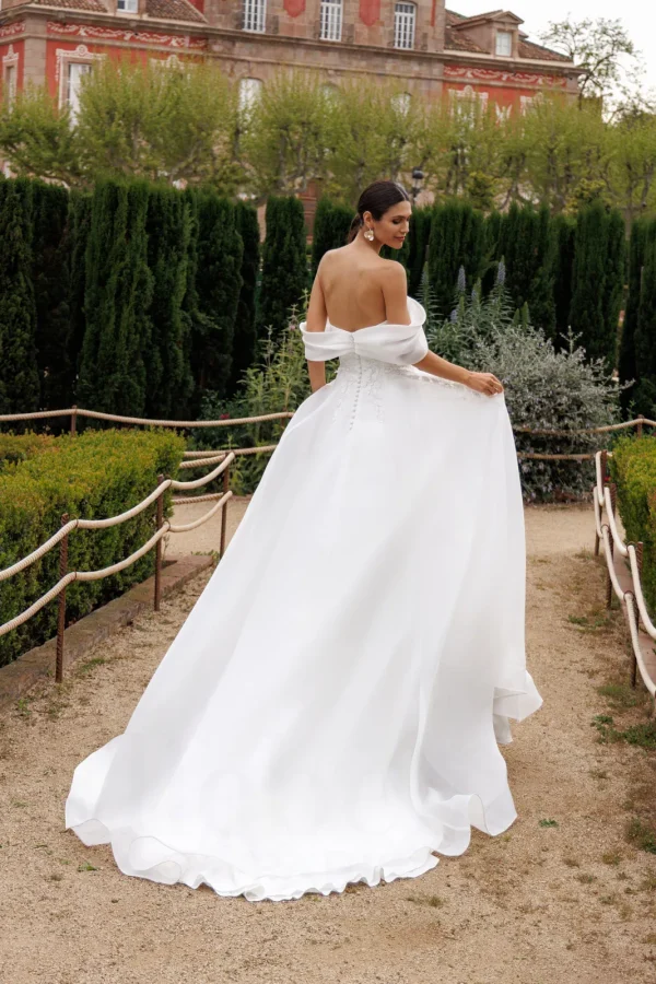 Dos boutonné et traîne en organza d'une robe de mariée trapèze à col Bardot