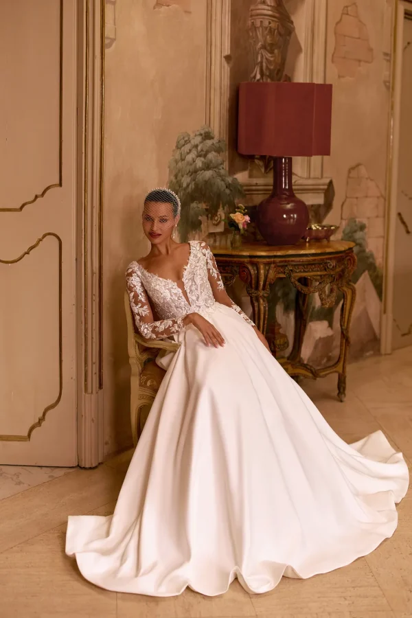 Mariée assise en robe trapèze en satin à manches longues en dentelle