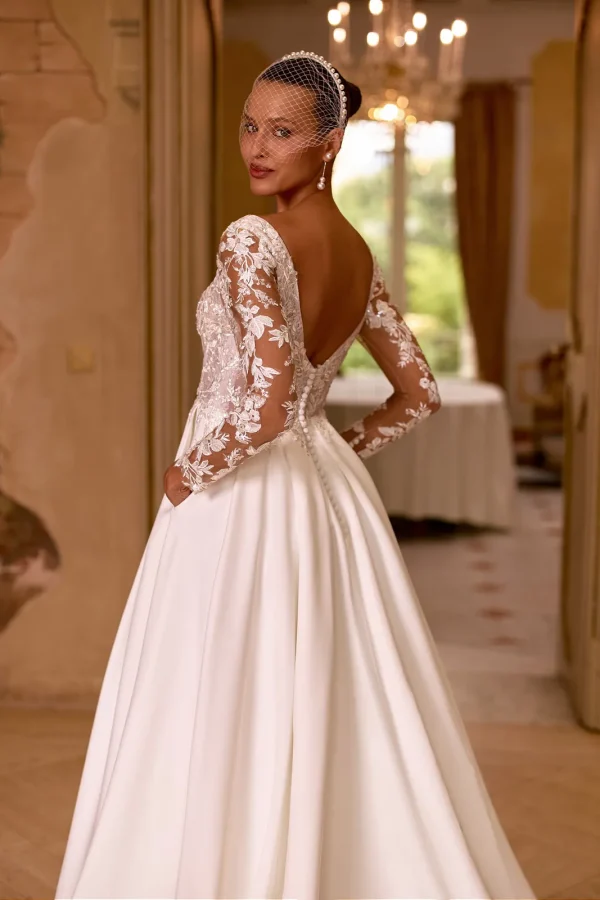 Dos nu en V boutonné et manches en dentelle d'une robe de mariée trapèze en satin