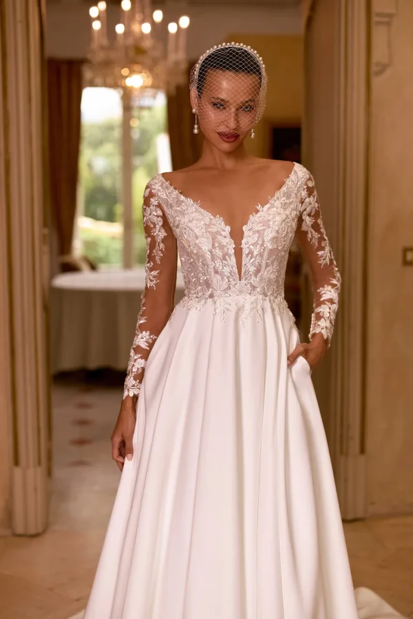 Manches longues transparentes et décolleté plongeant en dentelle d'une robe de mariée en satin