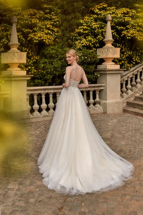 Dos nu et longue traîne d'une robe de mariée trapèze en tulle pailleté