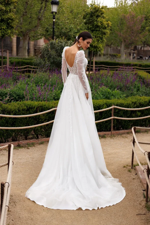 Dos nu arrondi et traîne d'une robe de mariée trapèze en tulle à manches longues