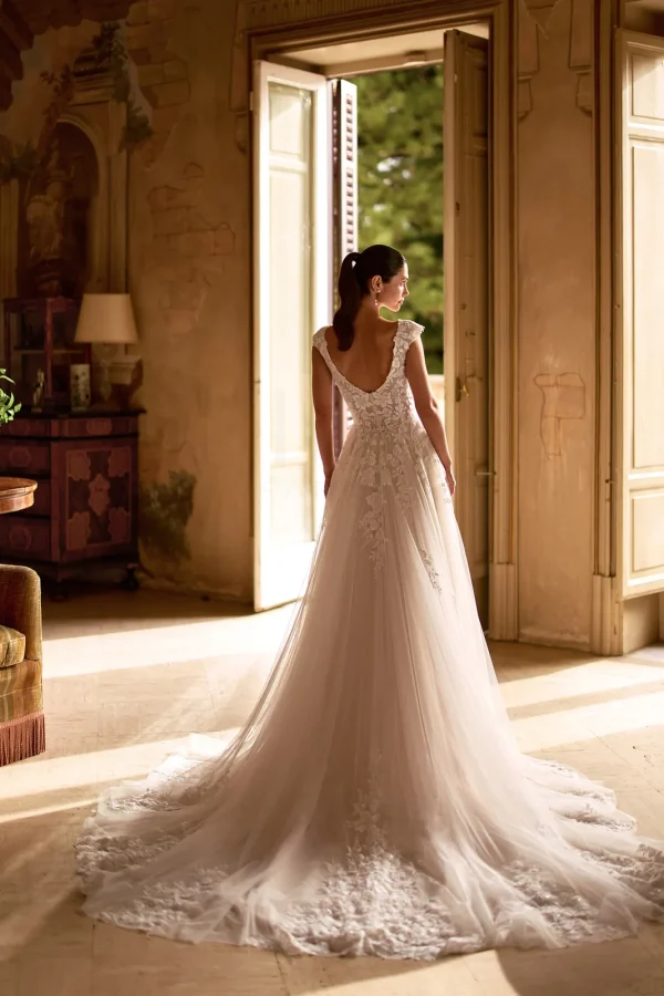 Dos nu arrondi et traîne en dentelle d'une robe de mariée trapèze en tulle nude