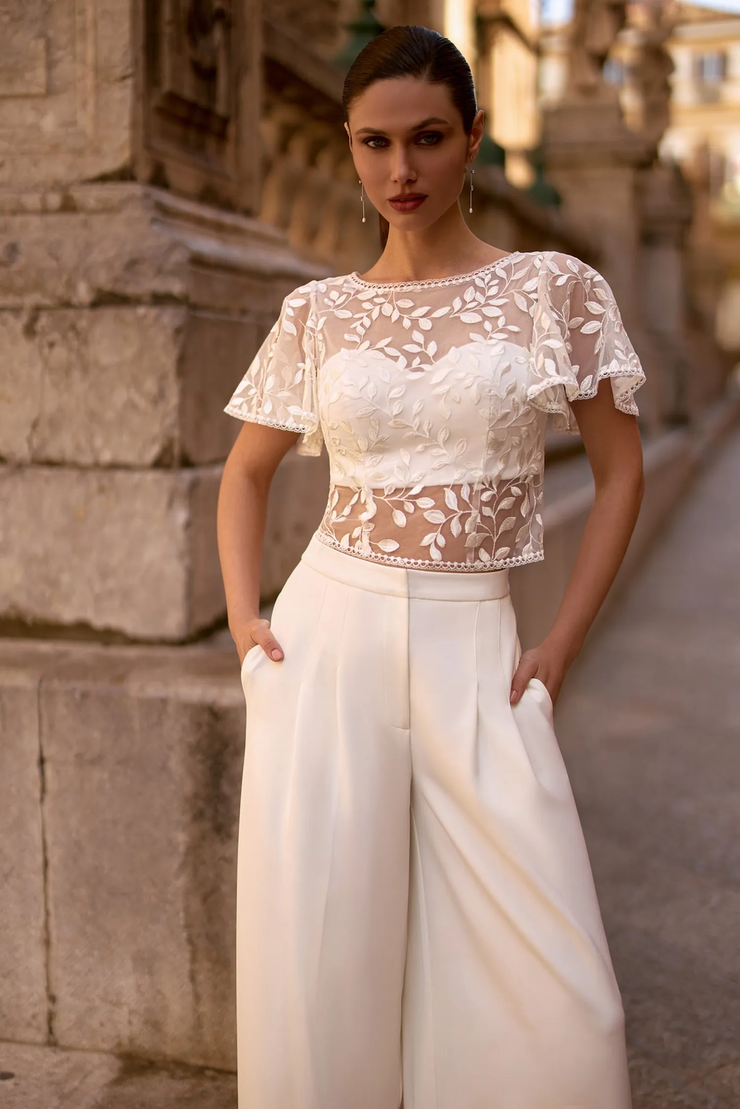 Boléro de mariée en dentelle à manches courtes BL8026 porté avec un pantalon vue de face Ellebeline